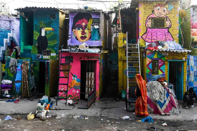 A woman walks past homes adorned with murals painted by artists from “Delhi Street Art” group at the Raghubir Nagar slum in New Delhi on December 2, 2019. (Photo by Sajjad Hussain/AFP Photo)