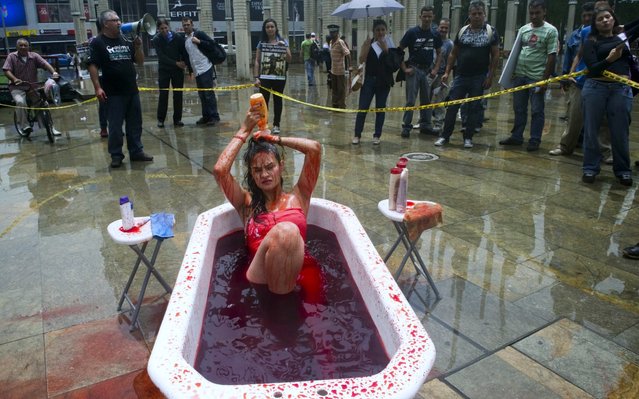 An animal rights activist washes herself with red dye to mimic blood during a protest against the testing of shampoo on animals in Barcelona