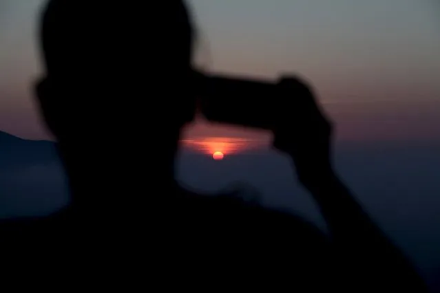 A hiker takes a picture of the sunrise while touring La Huasteca park, on the outskirts of Monterrey, Mexico, July 26, 2015. (Photo by Daniel Becerril/Reuters)