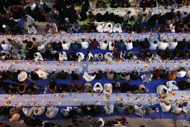 Iraqi Muslims gather to break their fast, with a collective meal along a street in the holy shrine city of Najaf, on April 22, 2022, during the Muslim month of Ramadan. (Photo by Ahmad Al-Rubaye/AFP Photo)