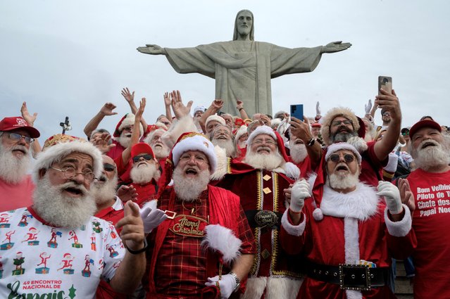 A group of Santa Claus sing during a visit to the Christ The Redeemer statue in Rio de Janeiro, Brazil on June 16, 2023, after attending the National Santa Claus Convention organized by Brazil's School of Santa Claus. (Photo by Mauro Pimentel/AFP Photo)