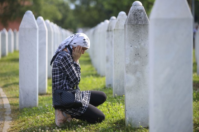 A Bosnian muslim woman mourns next to the grave of her relative, victim of the Srebrenica genocide, at the Memorial Centre in Potocari, Bosnia, Tuesday, July 11, 2023. Thousands gahter in the eastern Bosnian town of Srebrenica to commemorate the 28th anniversary on Monday of Europe's only acknowledged genocide since World War II. (Photo by Armin Durgut/AP Photo)