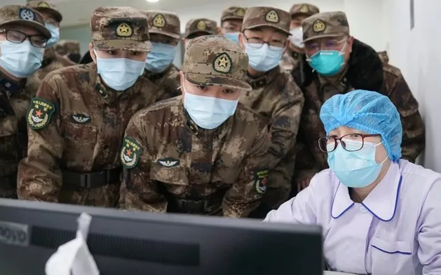 Members of a military medical team take over the work from a medical worker at Wuhan Jinyintan Hospital in Wuhan, central China's Hubei Province, on January 26, 2020. Three teams of military staff totaling 450, who flew to Wuhan on Friday night, immediately started work in three designated hospitals in Wuhan. (Photo by Cheng Min/Xinhua News Agency)