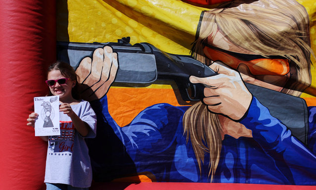 Six-year-old Rose Allen poses with the target she shot with a juvenile BB rifle at the Rod of Iron Freedom Festival, in Greeley, Pennsylvania, on October 12, 2024. (Photo by Brian Snyder/Reuters)