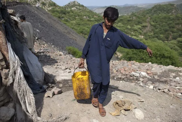 Samiullah, who says he is 14-years-old, carries water for his uncle's bath at a coal field in Choa Saidan Shah, Punjab province, May 5, 2014. (Photo by Sara Farid/Reuters)