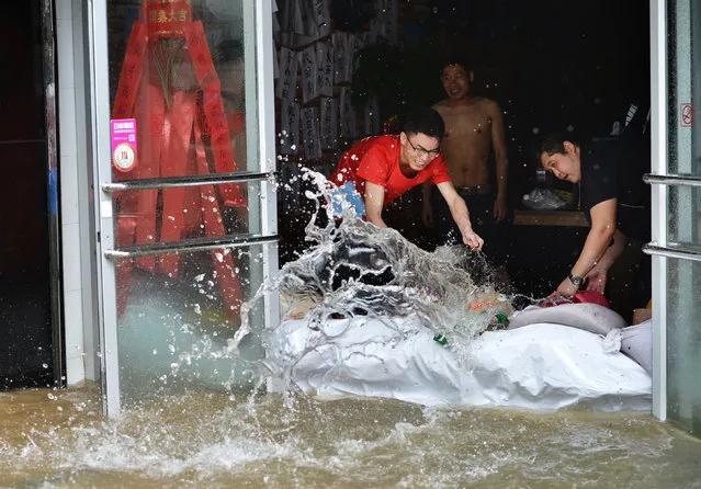 People remove flooded water from a restaurant in Wuhan, Hubei province, China, July 6, 2016. (Photo by Reuters/Stringer)