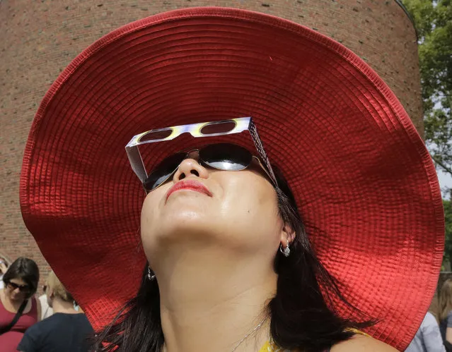 Ann Kim Tenhor, of Arlington, Mass., uses protective eclipse glasses to view a partial solar eclipse, Monday, August 21, 2017, on the campus of Massachusetts Institute of Technology, in Cambridge, Mass. (Photo by Steven Senne/AP Photo)