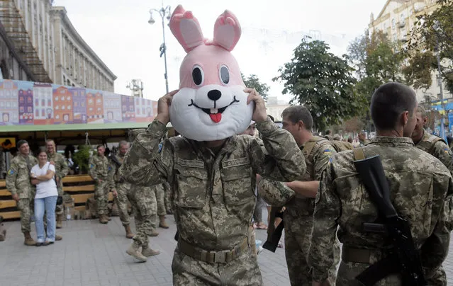 A soldier tries a cartoons character's costume on during a rehearsal for the Independence Day military parade in the center of Kiev, Ukraine, Saturday, August 22, 2015. (Photo by Efrem Lukatsky/AP Photo)