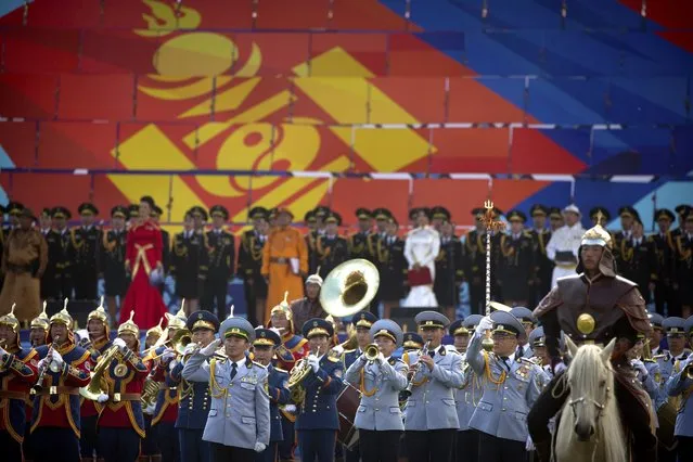 A marching band performs in front of a giant display of the Mongolian flag during the Naadam Festival in Ulaanbaatar, Mongolia, Monday, July 11, 2016. (Photo by Mark Schiefelbein/AP Photo)