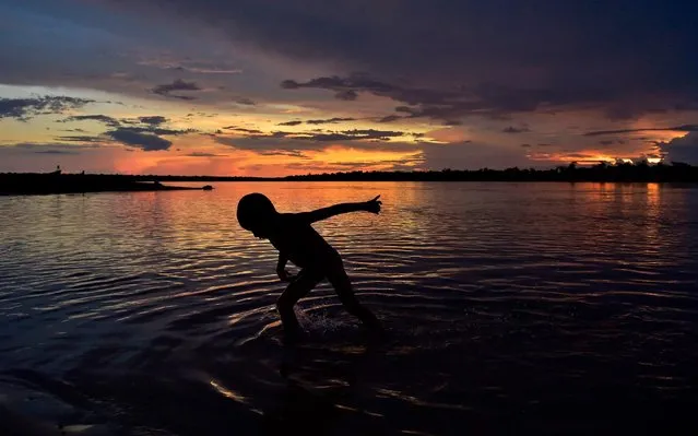 An Indigenous boy bathes in the river after a press conference of Indigenous leader Cacique Raoni Metuktire of the Kayapo tribe, in Piaracu village, near Sao Jose do Xingu, Mato Grosso state, Brazil, on January 15, 2020. (Photo by Carl de Souza/AFP Photo)