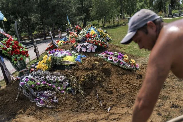 The graves of recently killed Ukrainian soldiers line a cemetery as a gravedigger covers the casket of Serhiy Marchenko following his burial service in Pokrovsk, Donetsk region, eastern Ukraine, Thursday, August 4, 2022. (Photo by David Goldman/AP Photo)