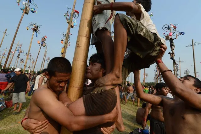 Indonesians participate in a local competition called “panjat pinang” in which people try to climb greased poles that have prizes and flags attached to the top, during an event to celebrate Indonesia's Independence Day in Jakarta on August 17, 2014. Indonesia marked the 69th anniversary of its independence from Dutch rule on August 17. (Photo by Romeo Gacad/AFP Photo)