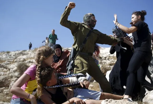 Palestinians scuffle with an Israeli soldier as they try to prevent him from detaining a boy during a protest against Jewish settlements in the West Bank village of Nabi Saleh, near Ramallah August 28, 2015. (Photo by Mohamad Torokman/Reuters)