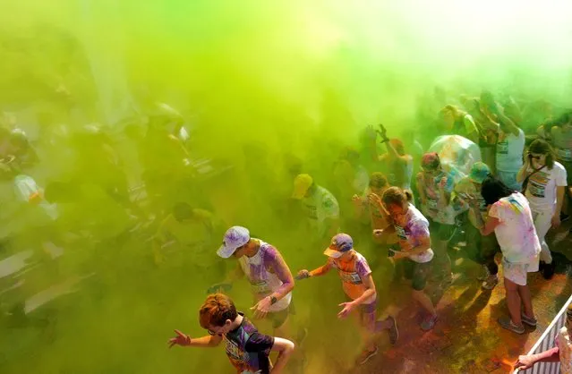 Colored powder is poured on participants during Color Run event in Jurmala, Latvia on August 14, 2022. (Photo by Ints Kalnins/Reuters)