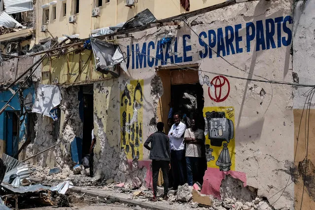 People stand at the entrance of a destored building after a deadly 30-hour siege by Al-Shabaab jihadists at Hayat Hotel in Mogadishu on August 21, 2022. At least 13 civilians lost their lives and dozens were wounded in the gun and bomb attack by the Al-Qaeda-linked group that began on Friday evening and lasted over a day, leaving many feared trapped inside the popular Hayat Hotel. (Photo by Hassan Ali Elmi/AFP Photo)