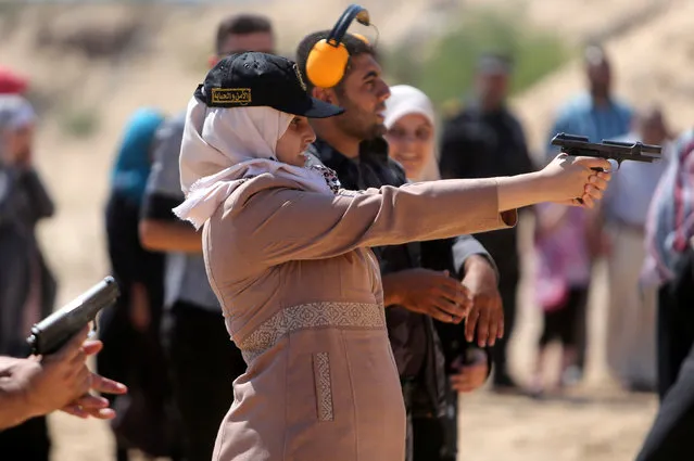 A Palestinian girl aims a pistol as she prepares to fire at a target during a training session for the families of Hamas officials, organized by Hamas-run Security and Protection Service, in Khan Younis in the southern Gaza Strip July 24, 2016. (Photo by Ibraheem Abu Mustafa/Reuters)