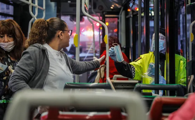 A local police delivers a mask to a woman at a bus on the first working day in Valencia after Easter holidays during the coronavirus (COVID-19) crisis on April 14, 2020 in Madrid, Spain. The Spanish government has started to ease the lockdown to revive the country's economy. (Photo by Rober Solsona/Europa Press via Getty Images)