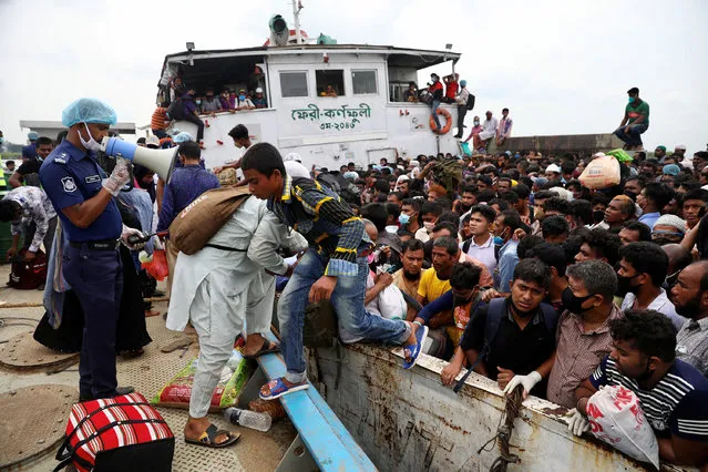 A police officer urges migrants who are trying to go home to celebrate Eid al-Fitr, to get off from an overcrowded ferry, after a boat capsized, amid concerns over the coronavirus disease (COVID-19) outbreak, in Munshiganj, Bangladesh, May 19, 2020. (Photo by Mohammad Ponir Hossain/Reuters)