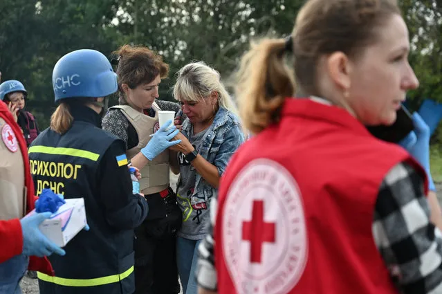 Psychologists help a person who was in a convoy of civilian vehicles, that was hit by a Russian missile strike amid Russia's attack on Ukraine, in Zaporizhzhia, Ukraine on September 30, 2022. (Photo by Reuters/Stringer)
