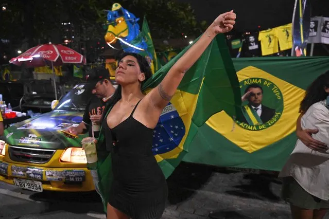Supporters of Brazilian President and re-election candidate Jair Bolsonaro react as they watch the vote count of the legislative and presidential election, in Rio de Janeiro, Brazil, on October 2, 2022. Brazilians voted Sunday in a polarizing presidential election which front-runner Luiz Inacio Lula da Silva hopes to take in the first round as incumbent Jair Bolsonaro says he will accept the result if it is “clean”. (Photo by Carl de Souza/AFP Photo)