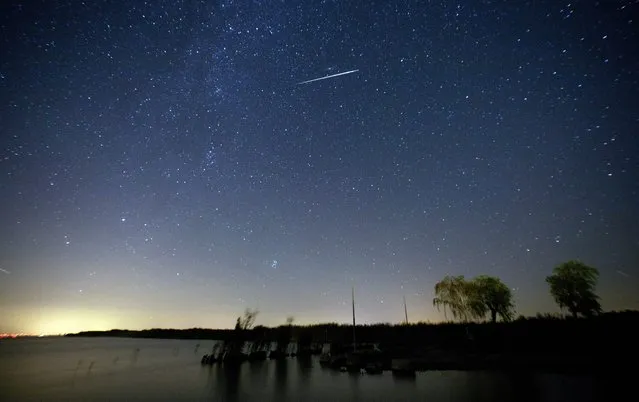 A picture taken with a slow shutter shows a meteor moving past stars in the night sky over lake Neusiedlersee near Moerbisch am See, around 70 km southeast of Vienna, Austria, early 12 August, 2016. The Perseid meteor shower is seen every August when the Earth passes through a stream of space debris left by Comet Swift-Tuttle. (Photo by Lisi Niesner/EPA)