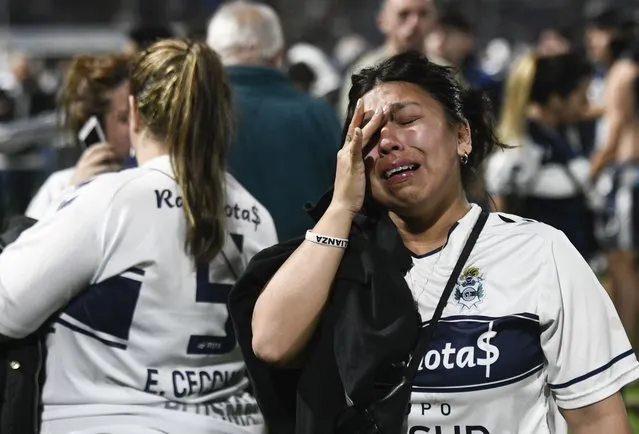 Fans of Gimnasia de La Plata react to tear gas on the field during a local tournament match between Gimnasia de La Plata and Boca Juniors in La Plata, Argentina, Thursday, October 6, 2022. The match was suspended after tear gas thrown by the police outside the stadium wafted inside affecting the players as well as fans who fled to the field to avoid its effects. (Photo by Gustavo Garello/AP Photo)