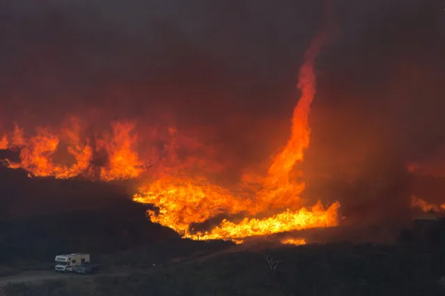 A fire tornado forms near cars parked on a country road at the Blue Cut Fire on August 17, 2016 near Wrightwood, California.. An unknown number of homes and businesses have burned and more than 80,000 people are under evacuation orders as the out-of-control wildfire spread beyond 30,000 acres and threatens to expand into the ski resort town of Wrightwood. (Photo by David McNew/Getty Images)