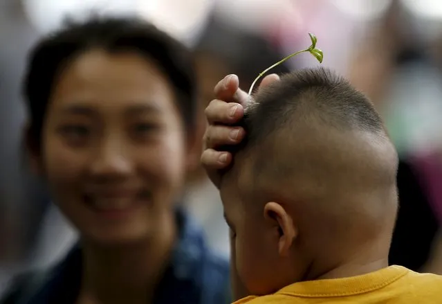 A woman tries a sprout-like hairpin on a baby on Nanluoguxiang street in Beijing, China, September 16, 2015. (Photo by Kim Kyung-Hoon/Reuters)