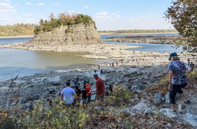 People visit Tower Rock, which is usually surrounded by water of the Mississippi River near Brazeau Township, Missouri, USA, 23 October 2022. Water levels in the river have dropped so low that visitors can walk to the site with dry feet. The Mississippi River, a main route of commercial barge traffic for grains, wheat, and coal, is historically low causing major supply chain disruptions. Barge freight rates have increased dramatically from draft levels reductions in the Mississippi River system as farmers harvest crops and need the river to get them to markets around the world. (Photo by Tannen Maury/EPA/EFE)