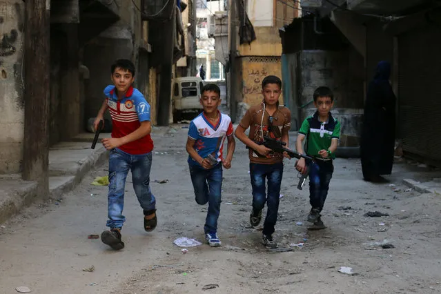 Syrian children play on a street with plastic toys guns in a rebel-held district of the northern city of Aleppo on July 6, 2016 during celebrations for Eid al-Fitr, which marks the end of the Muslim holy fasting month of Ramadan.. (Photo by Ameer Alhalbi/AFP Photo)