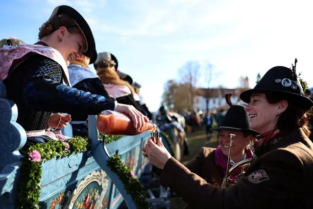 Farmers' wives, dressed in traditional Bavarian costumes, give out schnapps to the people from a wooden carriage on the way to the chapel on the Kalvarienberg during the Leonhardi Ritt procession, to pray to St Leonhard, the patron saint of animals, in Bad Toelz, Germany on November 7, 2022. (Photo by Lukas Barth/Reuters)