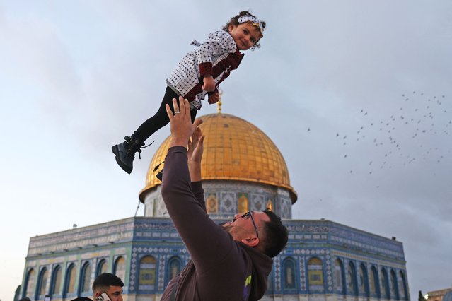 A man lifts a child as Muslims gather in front of the Dome of the Rock shrine in Jerusalem's Al-Agsa Mosque compound to celebrate the Eid al-Fitr, which marks the end of the holy fasting month of Ramadan, on March 30, 2025. (Photo by Ahmad Gharabli/AFP Photo)