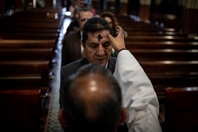 A priest makes the sign of the cross on the forehead of a man during the celebration of Ash Wednesday in Bogota, on February 14, 2024. (Photo by Luis Acosta/AFP Photo)