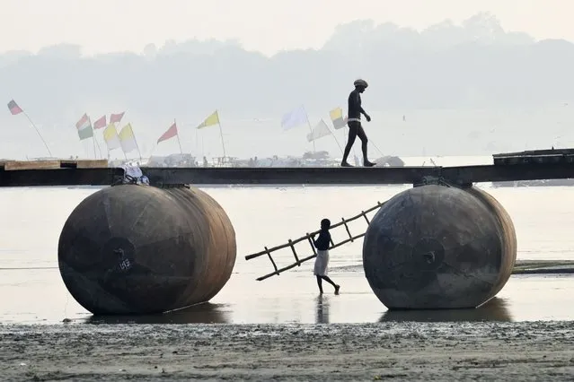 Labourers build a floating pontoon bridge on the Ganges River during preparations for the upcoming annual Hindu religious fair of Magh Mela in Prayagraj on December 6, 2022. (Photo by Sanjay Kanojia/AFP Photo)