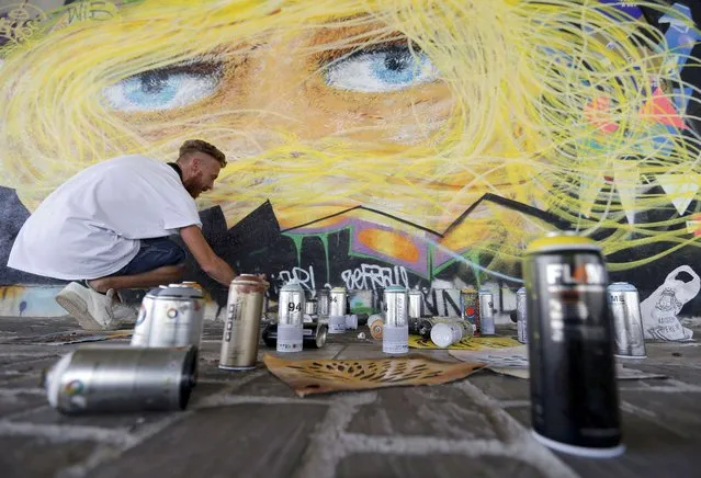 Cans of spray paint as seen as French street artist “Lapinthure” works on a wall creation, part of a Franco-Israeli cultural exchange, near a make-shift tent city where migrants live by the Institut francais de la mode (IFM) fashion school in Paris, France, August 21, 2015. (Photo by Regis Duvignau/Reuters)