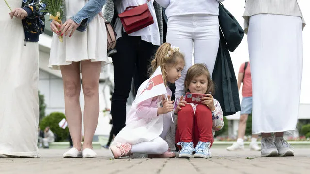 Young girls play with a phone during a protest in Minsk, Belarus, Saturday, August 22, 2020. Demonstrators are taking to the streets of the Belarusian capital and other cities, keeping up their push for the resignation of the nation's authoritarian leader. President Alexander Lukashenko has extended his 26-year rule in a vote the opposition saw as rigged. (Photo by Evgeniy Maloletka/AP Photo)