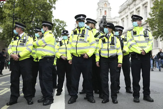 Police officers wearing face masks stand guard during a protest opposed to COVID-19 pandemic restrictions, in Trafalgar Square, London, Saturday, August 29, 2020. (Photo by Yui Mok/PA Wire via AP Photo)
