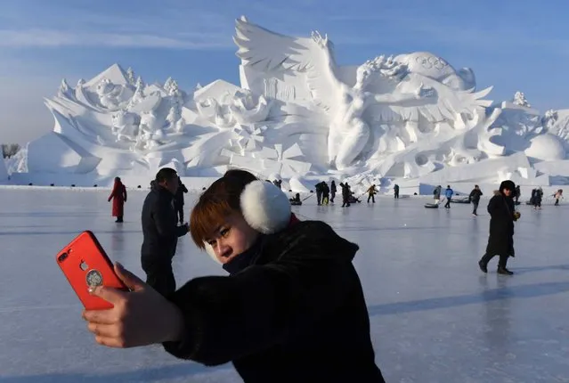 A woman takes a selfie before the opening of the annual Harbin Ice and Snow Sculpture Festival in Harbin in China's northeast Heilongjiang province on January 5, 2018. The festival attracts hundreds of thousands of visitors annually. (Photo by Greg Baker/AFP Photo)