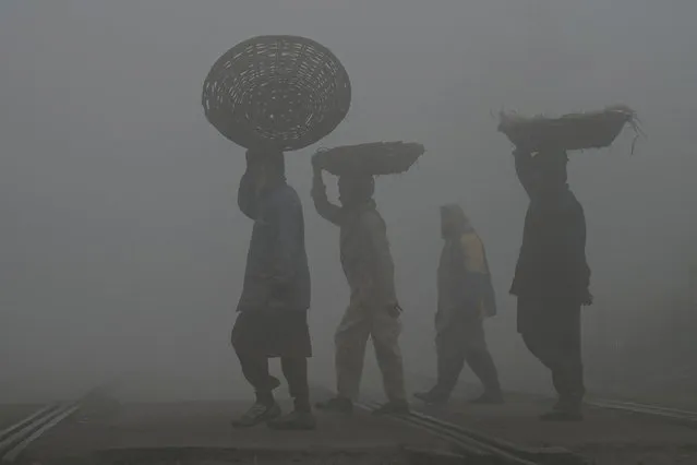 Labourers arrive at fruit market amid smoggy and foggy conditions early in the morning in Lahore on January 3, 2023. (Photo by Arif Ali/AFP Photo)