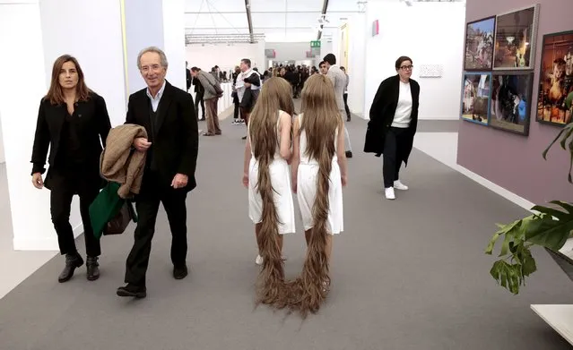 Twin sisters who are part of a performance artwork entitled "Siamese Hair Twins" by Tunga, walk through the galleries at the Frieze Art Fair in London, Britain October 14, 2015. (Photo by Suzanne Plunkett/Reuters)