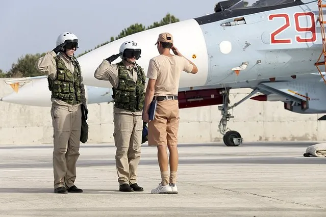A ground crew member reports to pilots that their Sukhoi Su-30 fighter jet is ready for a combat mission at Hmeymim air base near Latakia, Syria, in this handout photograph released by Russia's Defence Ministry, October 22, 2015. (Photo by Reuters/Ministry of Defence of the Russian Federation)