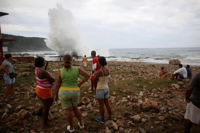 People watch waves splashing on the beach at Siboney ahead of the arrival of Hurricane Matthew in Cuba, October 4, 2016. (Photo by Alexandre Meneghini/Reuters)