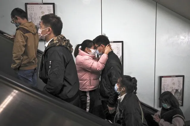 A couple wearing face masks to help curb the spread of the coronavirus hug each other as they exit a subway station with commuters during the morning rush hour in Beijing, Thursday, October 29, 2020. (Photo by Andy Wong/AP Photo)