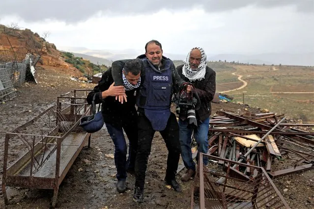 Palestinians carry away photojournalist Ayman Nobani who has been wounded by Israeli gunfire while covering clashes in the occupied West Bank village of Duma on February 2, 2023 following the demolition of a Palestinian owned house, built without a permit from the Israeli authorities in the area C which lies under their control since 1967. (Photo by Zain Jaafar/AFP Photo)