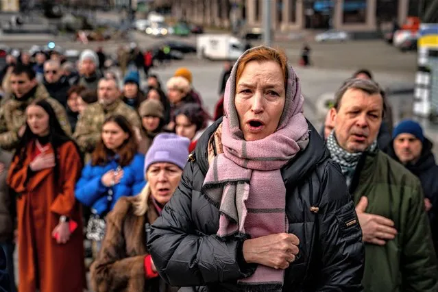 People sing the Ukrainian national anthem during a ceremony for slain Ukrainian volunteers Yuriy Horovets, Maksym Mykhaylov, Taras Karpyuk, and Bohdan Lyagov in the Independence Square in Kyiv on March 7, 2023, amid the Russian invasion of Ukraine. Hundreds of mourners packed a Kyiv church on March 7, for the funeral of volunteers killed on a sabotage mission in Russia, following a spate of attacks along Moscow's frontier. Mourners, many in camouflage and covering their faces, attended a service in a central church for four men – one still a teenager – killed in December during an incursion into Russia's southern Bryansk region. (Photo by Dimitar Dilkoff/AFP Photo)