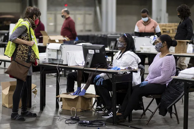 A GOP observer, left, watches as workers scan ballots as the Fulton County presidential recount gets under way Wednesday morning, November 25, 2020 at the Georgia World Congress Center in Atlanta. County election workers across Georgia have begun an official machine recount of the roughly 5 million votes cast in the presidential race in the state. The recount was requested by President Donald Trump after certified results showed him losing the state to Democrat Joe Biden by 12,670 votes, or 0.25%. (Photo by Ben Gray/AP Photo)