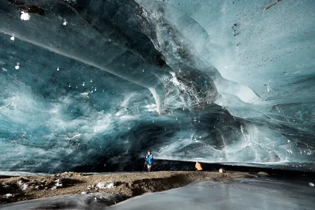 A photographer takes a picture in the “Mill”, a 20m long natural ice cave created by melted water accumulated during the summer and by a siphon effect leaves in the autumn giving way to an ice cathedral, at the Glacier 3000 ski resort in Les Diablerets, Switzerland, December 10, 2020. (Photo by Denis Balibouse/Reuters)