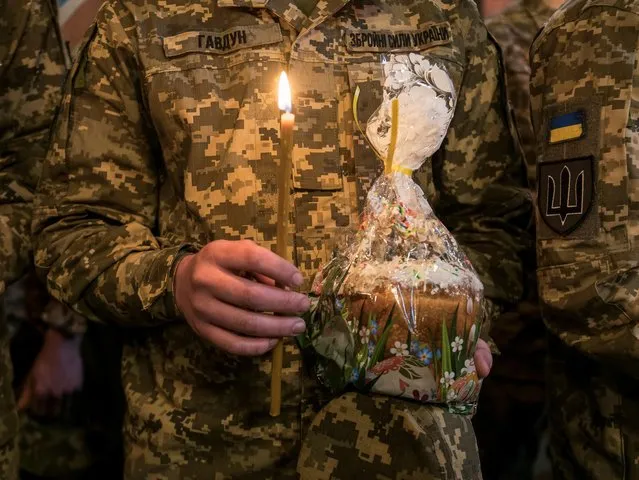 A Ukrainian serviceman with Easter cake attends a special service for Ukrainian Armed Forces, amid Russia's attack on Ukraine, during a ceremony to bless Easter cakes at St Michael's Cathedral before Orthodox Christmas in Kyiv, Ukraine on April 12, 2023. (Photo by Vladyslav Musiienko/Reuters)
