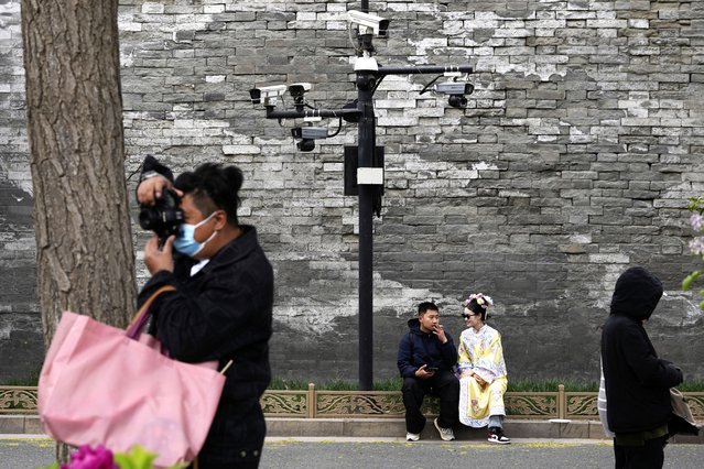 A woman in traditional Chinese clothing talks with a man underneath security cameras outside the Forbidden City in Beijing, Saturday, April 12, 2025. (Photo by Ng Han Guan/AP Photo)