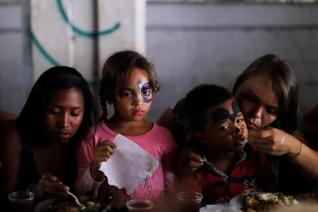 Women and children enjoy a plate of food donated by Venezuelan presidential candidate Javier Bertucci of the “Esperanza por el Cambio” party, as part of Mother's Day, during a campaign rally in Caracas, Venezuela May 13, 2018. (Photo by Carlos Jasso/Reuters)